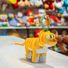 Load image into Gallery viewer, Minecraft 5 Inch Cat Bag Hanger Plush with pixelated design on a store counter.
