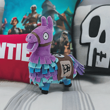 Load image into Gallery viewer, Fortnite Loot Llama 6-inch plush with vibrant colors and detailed stitching on a bed with Fortnite-themed pillows.
